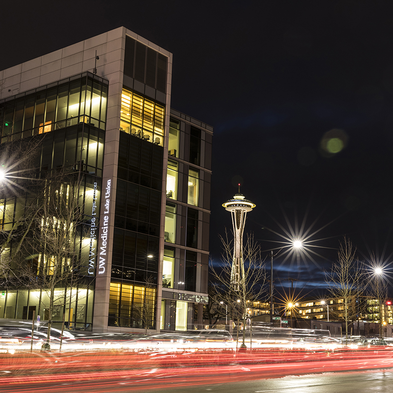 A night shot of the UW Medicine South Lake Union Building, with the Space Needle in the background. 