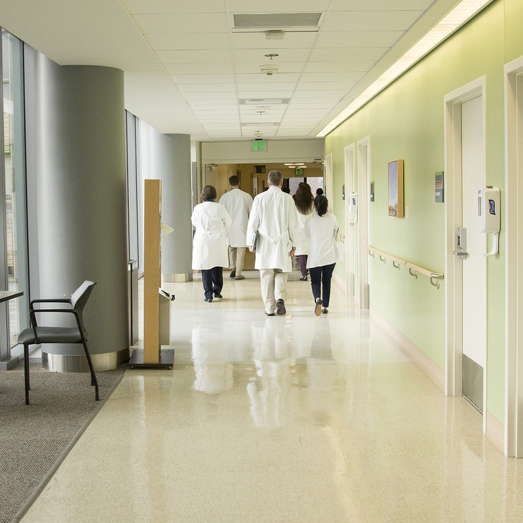 A group of clinicians in lab coats walk down a hallway at Harborview Medical Center.