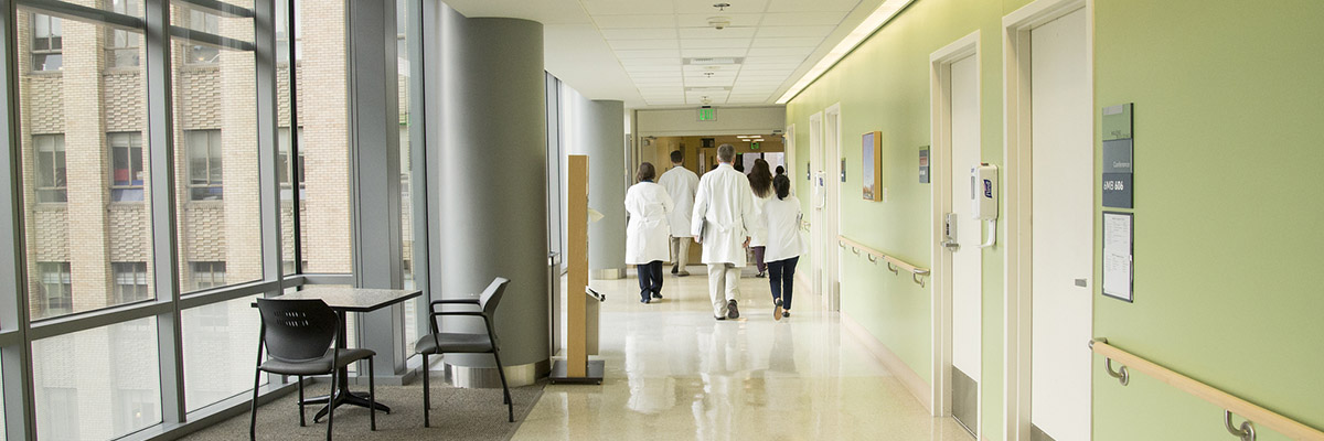 A group of doctors in lab coats walk down a hallway