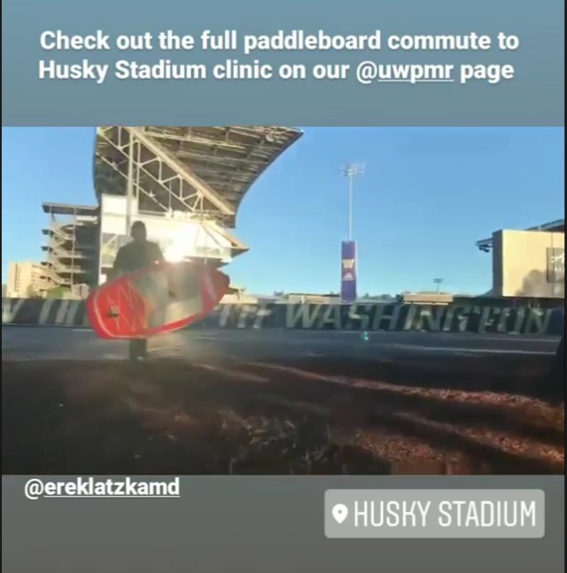 A person carries a paddleboard into Husky Stadium, which is one possible commute to work!