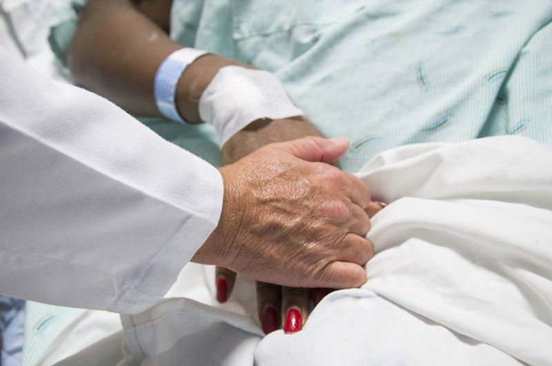 A doctor holds a patient's hand at the HMC Burn Center. 