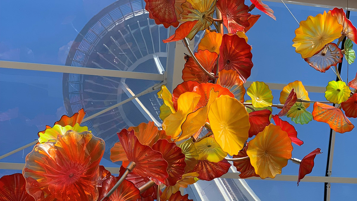 Looking up at the Space Needle past red and yellow glass at Chihuly Garden. 